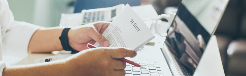 Business man review his resume on his desk, laptop computer, calculator and cup of coffee,Seleted focus.